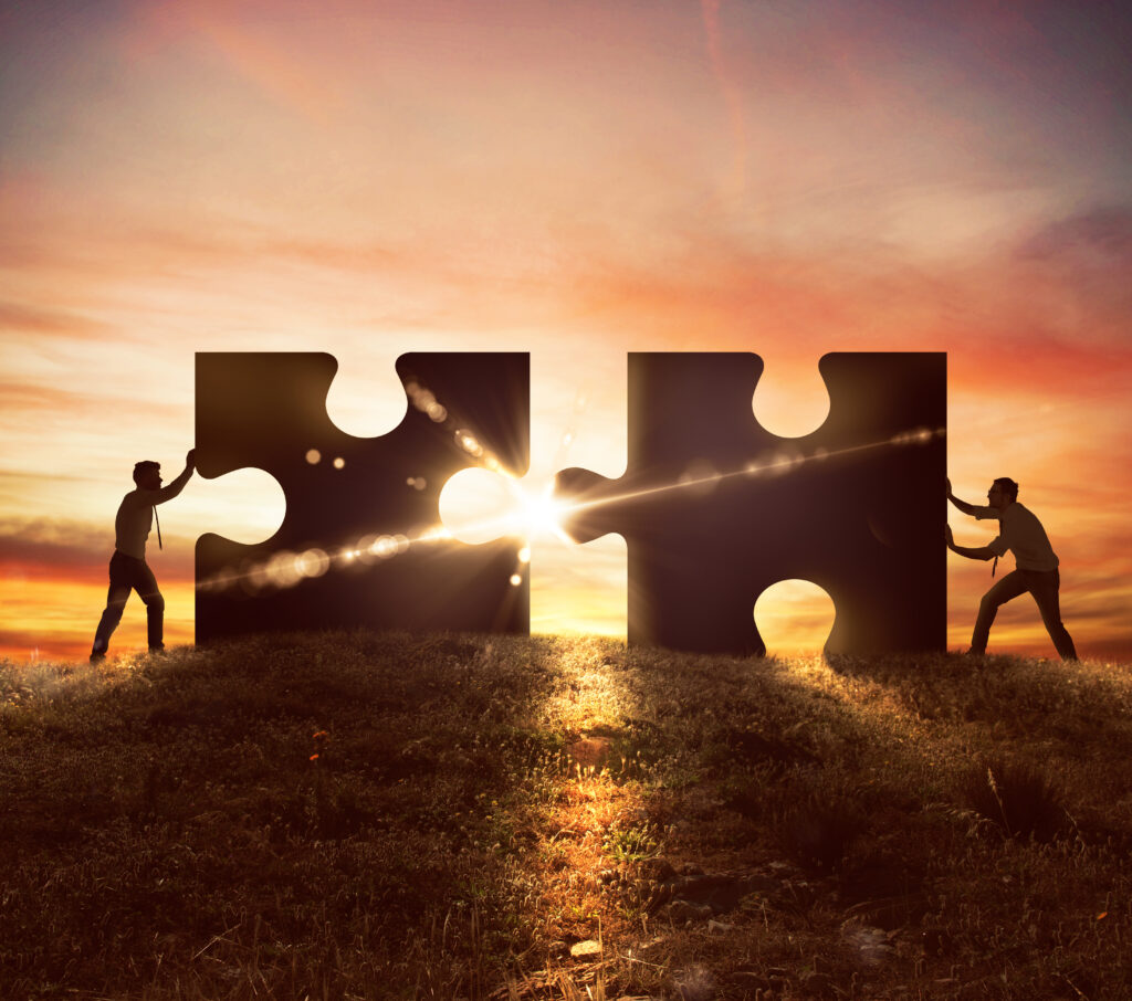 Men push two puzzle pieces at sunset